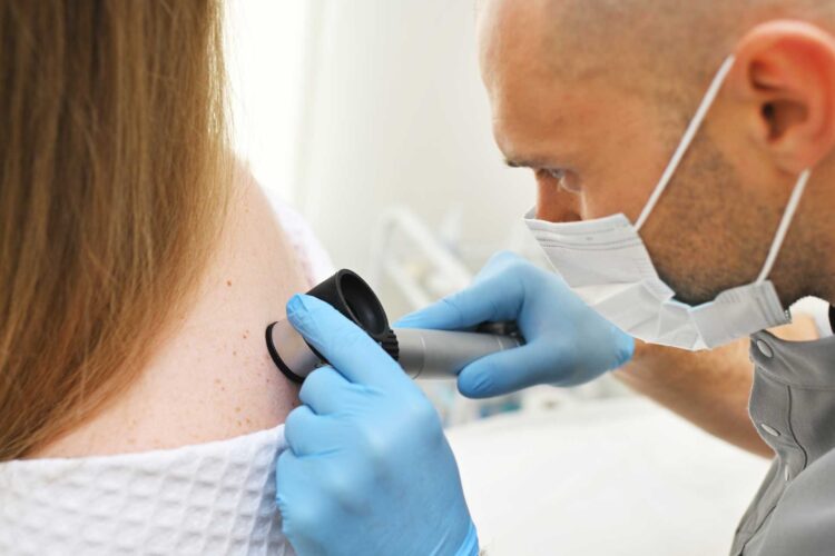 Skin doctor performing skin check and skin cancer assessment on a patient